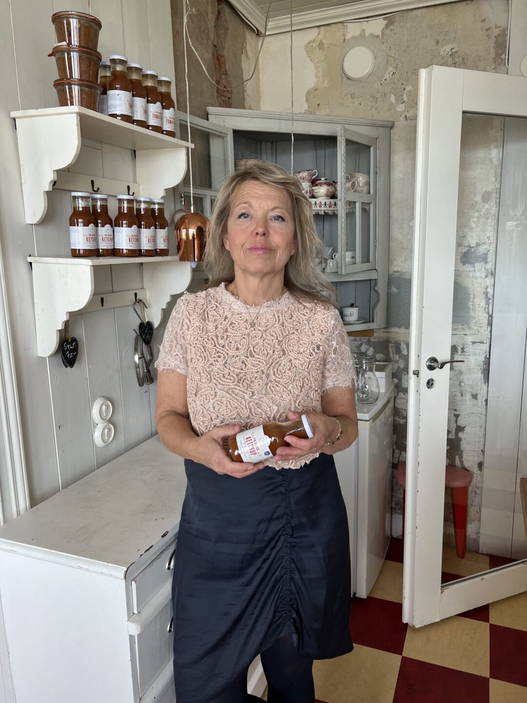 Kvinna med en glasflaska i händerna, ståendes i ett kök